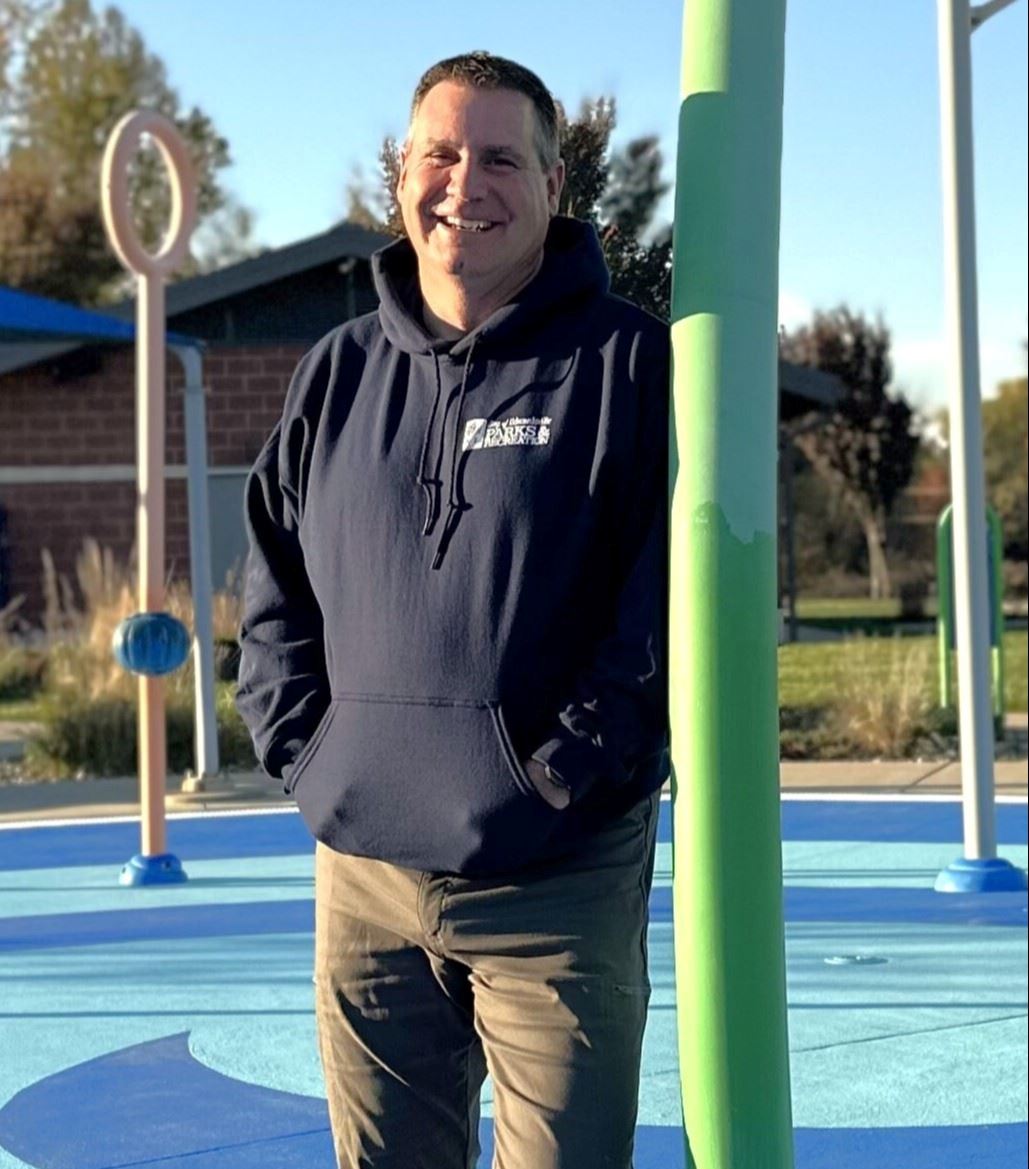 Man in a blue shirt stands outside at a water park